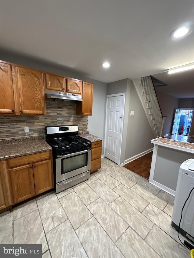 kitchen with dark stone countertops, tasteful backsplash, and stainless steel gas range oven