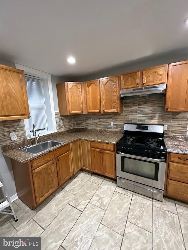 kitchen featuring stainless steel gas range oven, sink, and backsplash