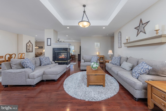 living area with dark wood finished floors, a tray ceiling, recessed lighting, and a tile fireplace