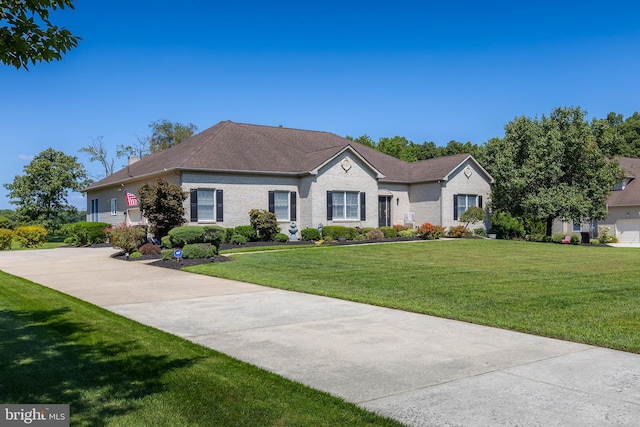 view of front of home featuring driveway, a front lawn, and brick siding