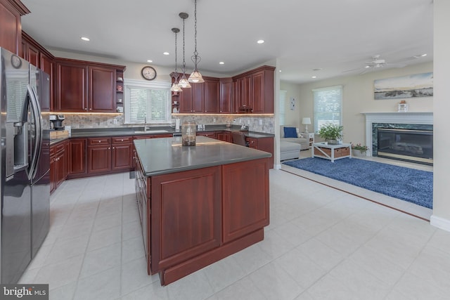 kitchen with open floor plan, stainless steel refrigerator with ice dispenser, reddish brown cabinets, open shelves, and dark countertops