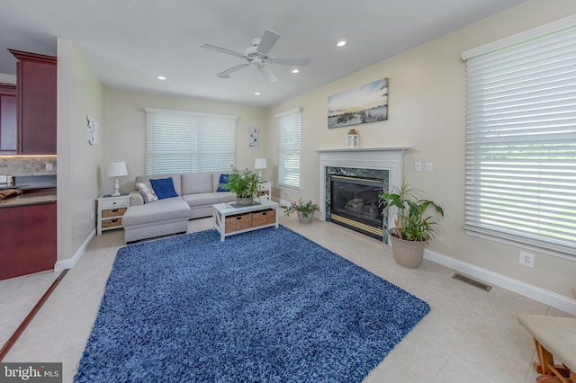 living room featuring light tile patterned floors, a wealth of natural light, a premium fireplace, and visible vents