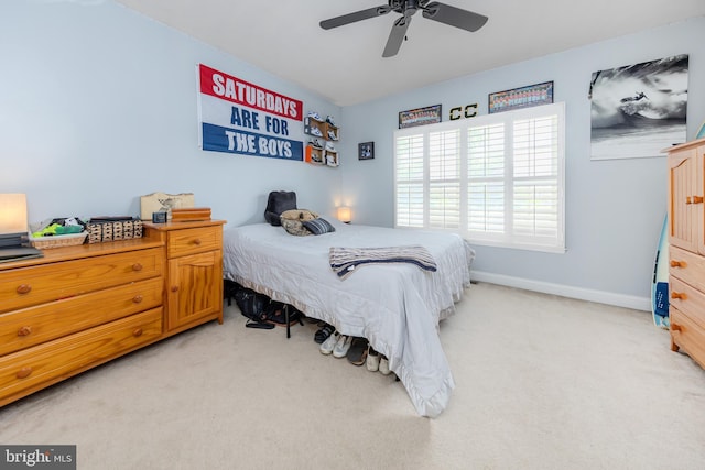 bedroom featuring light carpet, a ceiling fan, and baseboards