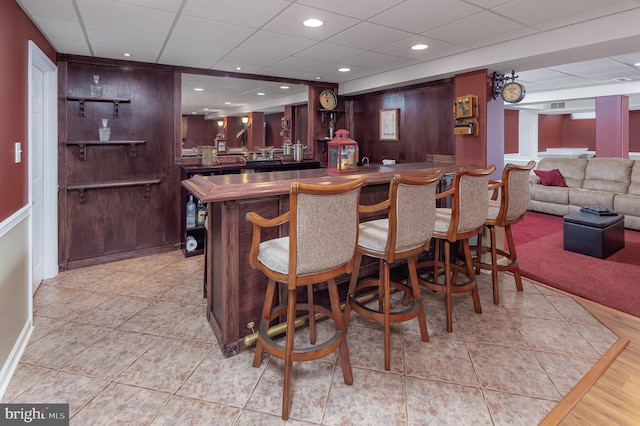 bar with light tile patterned floors, recessed lighting, bar, and a drop ceiling