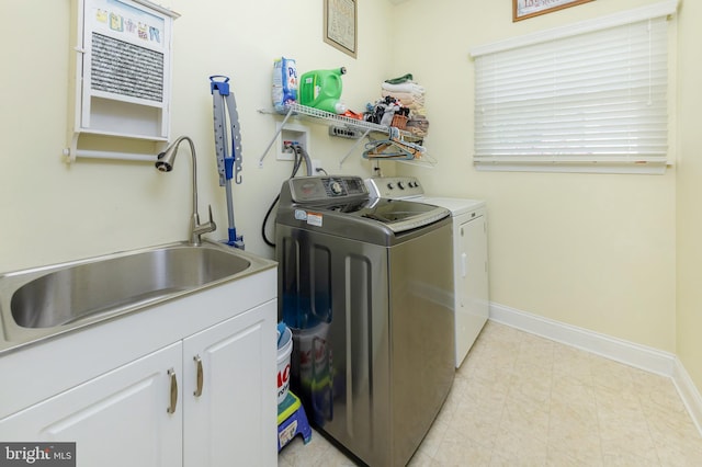 clothes washing area featuring washing machine and clothes dryer, cabinet space, baseboards, and a sink