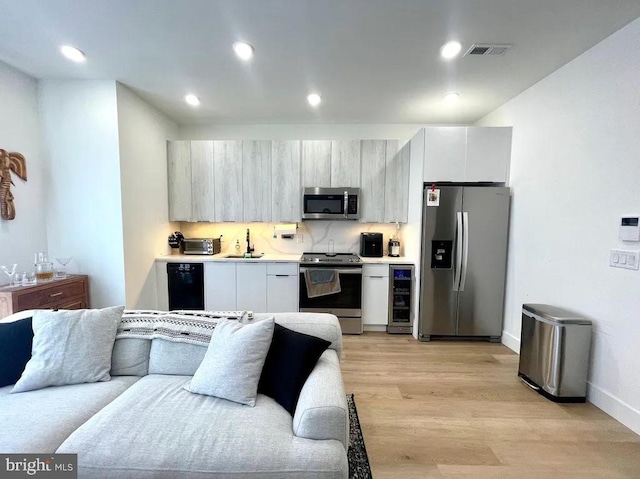 kitchen featuring backsplash, sink, light hardwood / wood-style flooring, beverage cooler, and stainless steel appliances