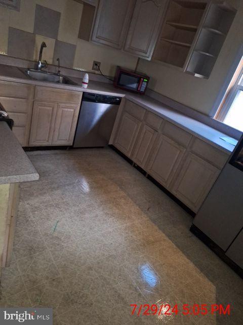 kitchen with light brown cabinets, dishwasher, sink, and light tile patterned flooring