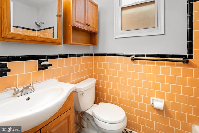 bathroom with vanity, tile walls, and toilet