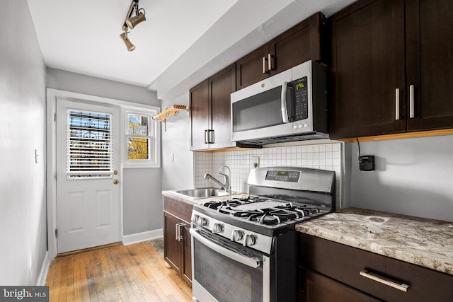 kitchen featuring stainless steel appliances, sink, tasteful backsplash, light hardwood / wood-style flooring, and dark brown cabinetry