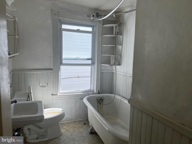 bathroom featuring wooden walls, toilet, a bathing tub, and sink