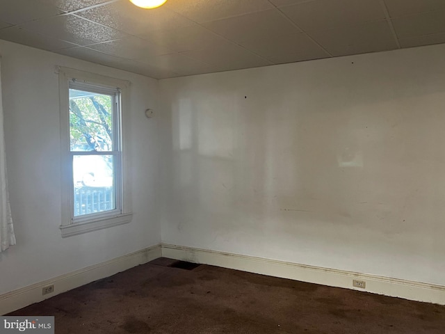 carpeted spare room with a drop ceiling