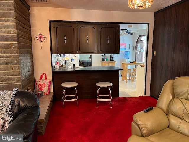 kitchen with ceiling fan, dark brown cabinets, carpet floors, and kitchen peninsula