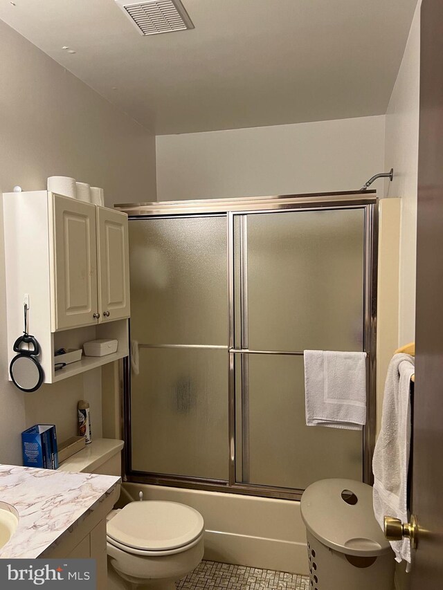 full bathroom featuring vanity, toilet, bath / shower combo with glass door, and tile patterned flooring