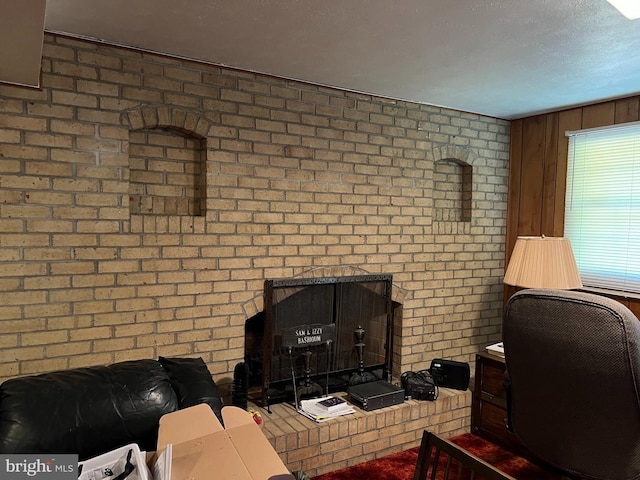 living room featuring a fireplace, a textured ceiling, and brick wall