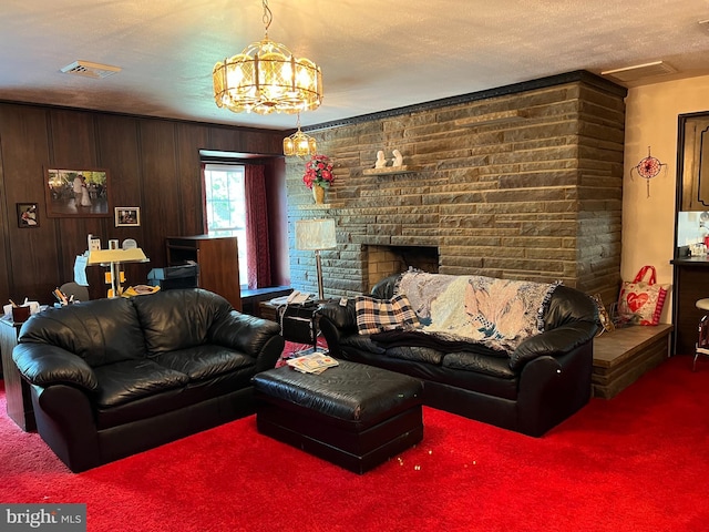 carpeted living room with a fireplace, wooden walls, a textured ceiling, and an inviting chandelier