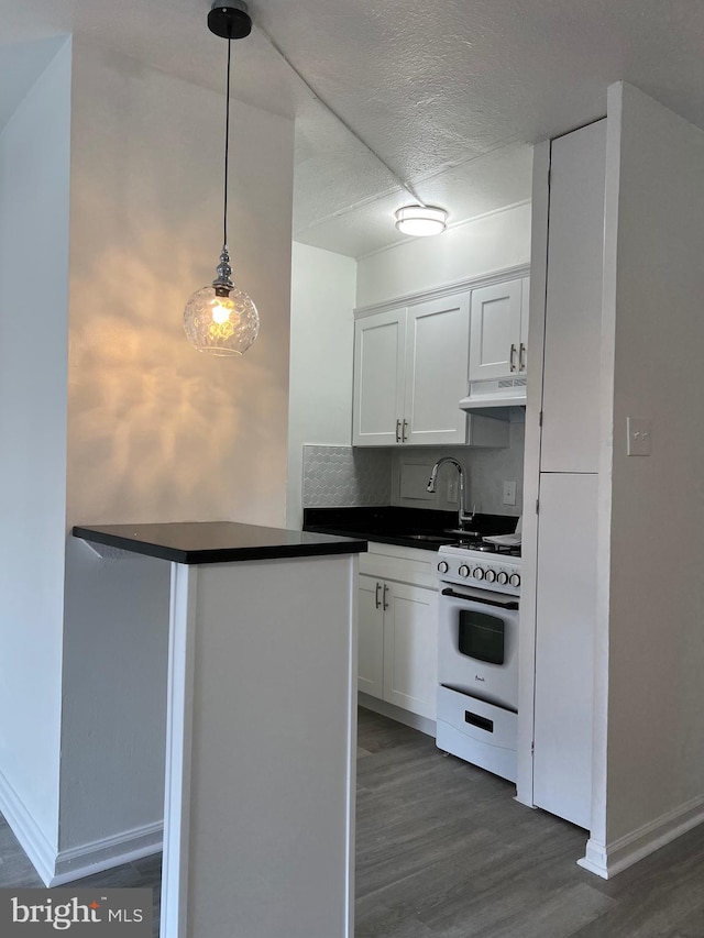 kitchen featuring dark hardwood / wood-style floors, white cabinetry, kitchen peninsula, hanging light fixtures, and white range with gas stovetop