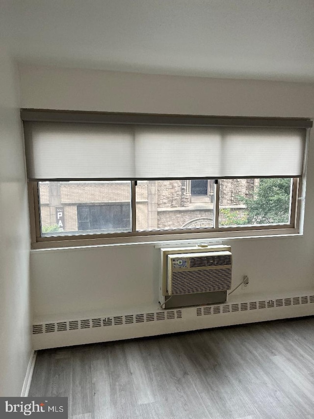 unfurnished room featuring baseboard heating and wood-type flooring