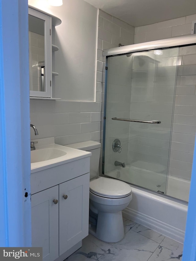 full bathroom featuring tile walls, toilet, vanity, tile patterned flooring, and bath / shower combo with glass door