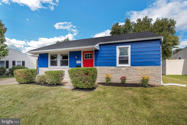 single story home with a front yard, stone siding, and fence