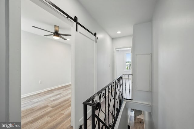 hallway with light hardwood / wood-style floors and a barn door