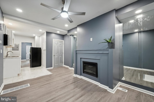 living room featuring light hardwood / wood-style floors, sink, and ceiling fan