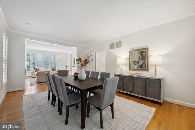 dining area with crown molding and light hardwood / wood-style flooring