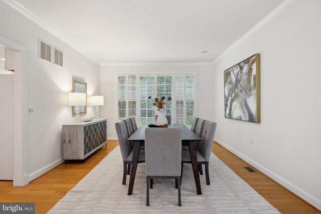 dining room with ornamental molding and light hardwood / wood-style floors