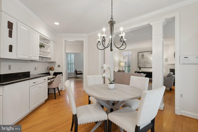 dining area featuring crown molding, light hardwood / wood-style flooring, ornate columns, and a chandelier