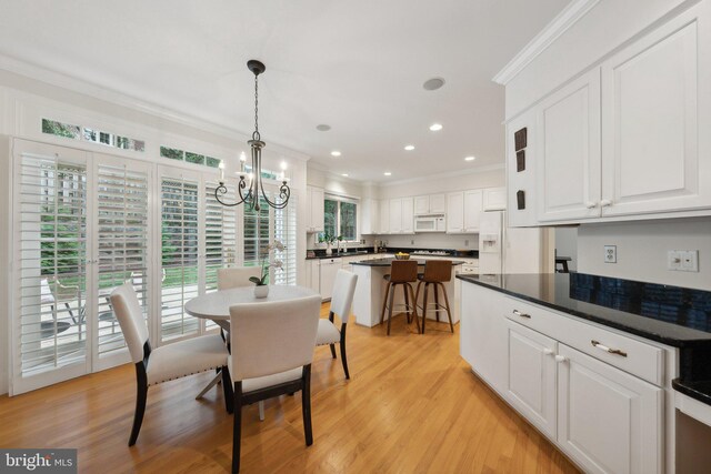 dining room with a wealth of natural light, ornamental molding, a chandelier, and light hardwood / wood-style floors