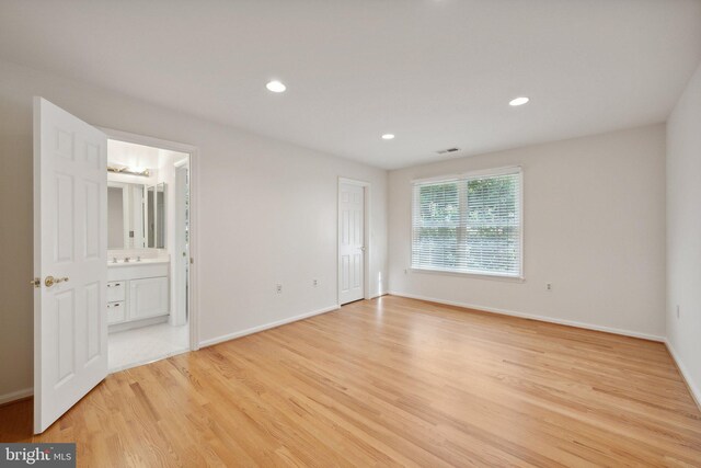 unfurnished bedroom featuring light wood-type flooring and connected bathroom