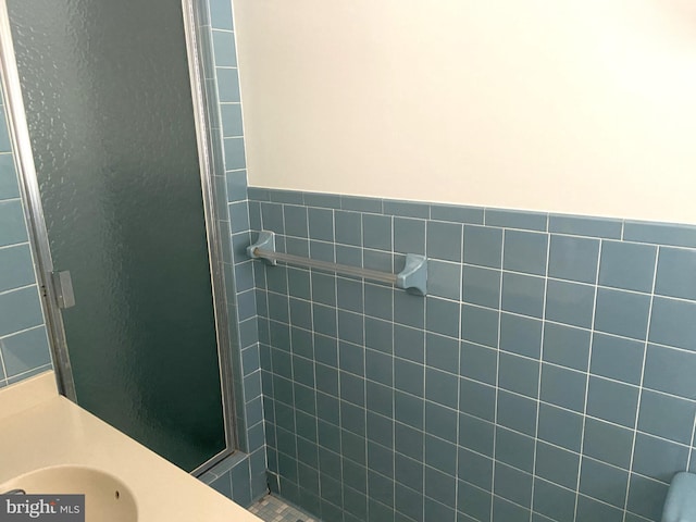 bathroom with tile walls, sink, and a shower with shower door