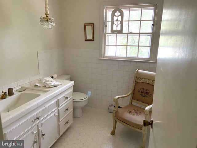 bathroom featuring tile walls, toilet, tile patterned floors, vanity, and an inviting chandelier