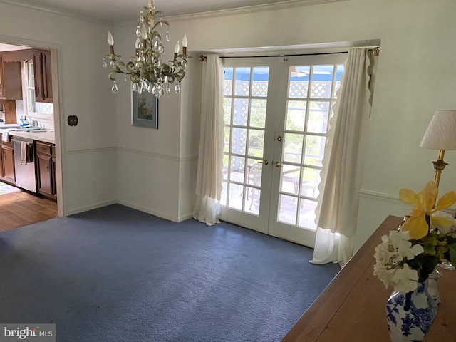 doorway to outside featuring crown molding, french doors, carpet, and an inviting chandelier