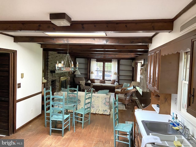 dining area with sink, brick wall, hardwood / wood-style flooring, and beam ceiling