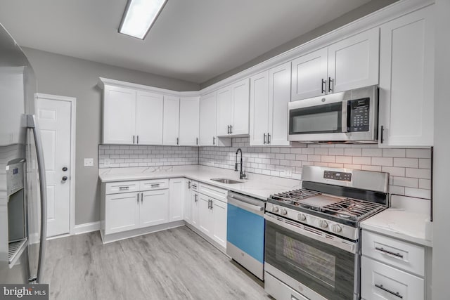 kitchen featuring stainless steel appliances, light wood-type flooring, a sink, and white cabinets