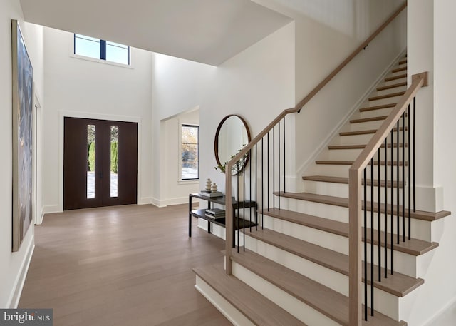 entryway with french doors, baseboards, a high ceiling, and wood finished floors