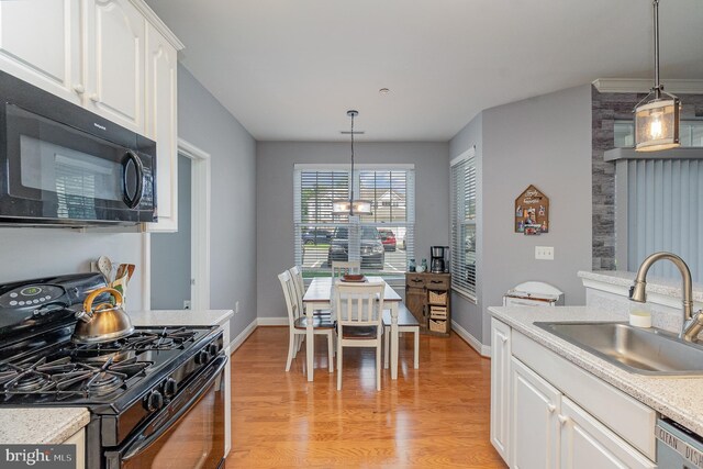 kitchen featuring black appliances, sink, pendant lighting, white cabinets, and light hardwood / wood-style flooring