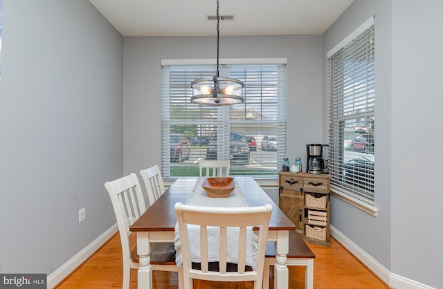 dining space featuring light hardwood / wood-style floors, a wealth of natural light, and an inviting chandelier