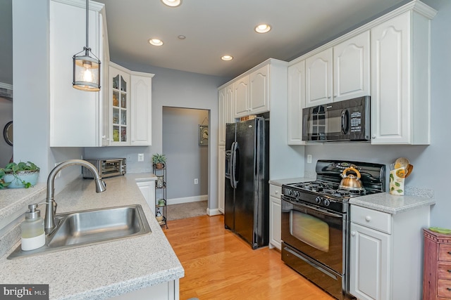 kitchen featuring light stone countertops, black appliances, sink, light wood-type flooring, and white cabinetry