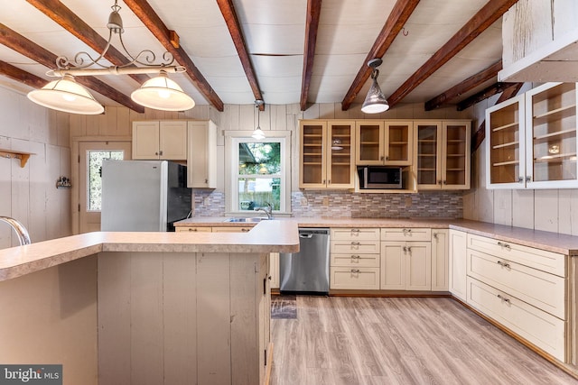 kitchen with decorative light fixtures, light hardwood / wood-style flooring, cream cabinetry, stainless steel appliances, and backsplash