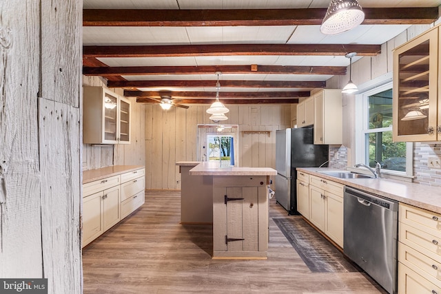 kitchen with cream cabinets, a kitchen island, hanging light fixtures, and appliances with stainless steel finishes