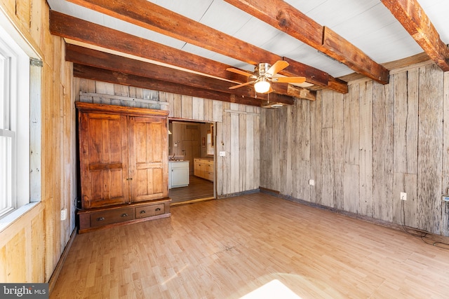 unfurnished bedroom featuring multiple windows, beam ceiling, light hardwood / wood-style flooring, and wooden walls