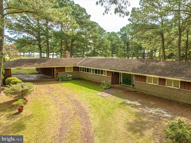 single story home with driveway, a chimney, a front lawn, board and batten siding, and brick siding