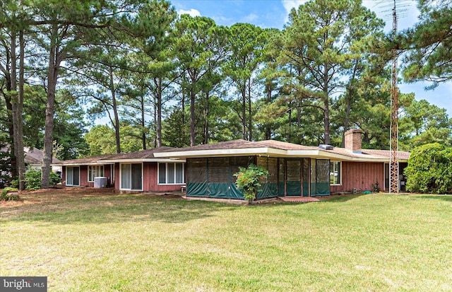 ranch-style house featuring a sunroom, a chimney, a front lawn, and central AC