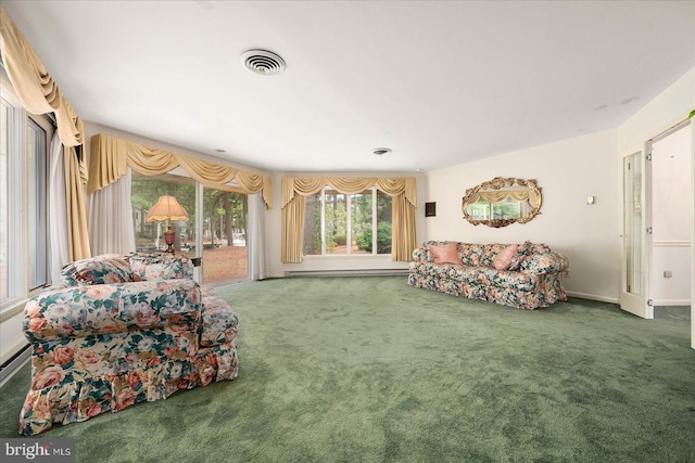 living room with carpet floors, visible vents, and a baseboard heating unit