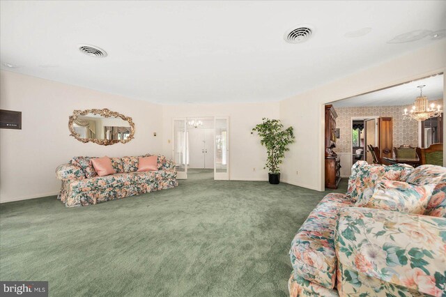 carpeted living area with wallpapered walls, visible vents, and a chandelier