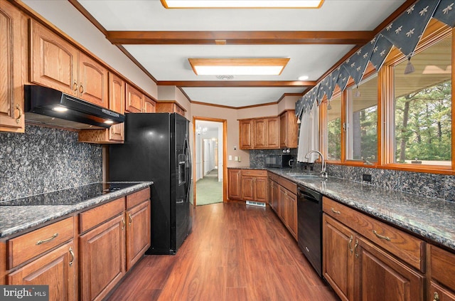 kitchen featuring under cabinet range hood, dark wood-type flooring, a sink, brown cabinets, and black appliances