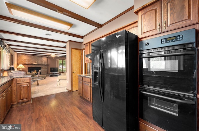 kitchen with dark wood-style floors, open floor plan, black appliances, a fireplace, and beam ceiling