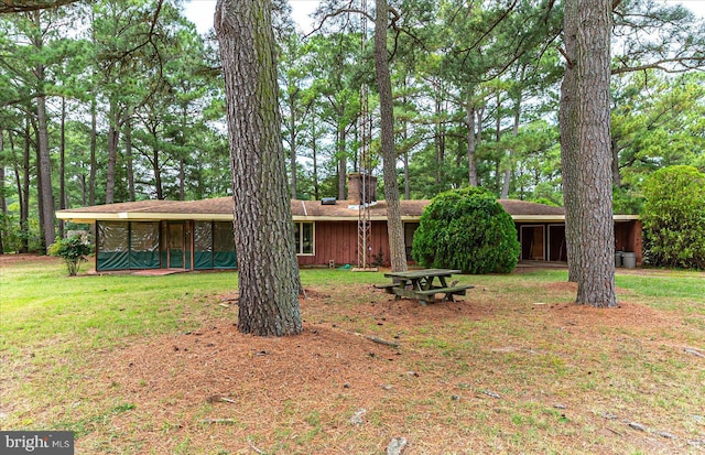 rear view of property with a lawn and a sunroom