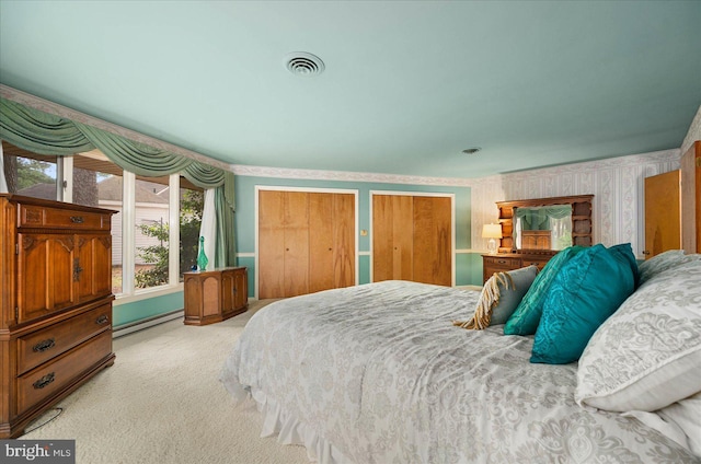 bedroom with a baseboard heating unit, visible vents, carpet, two closets, and wallpapered walls